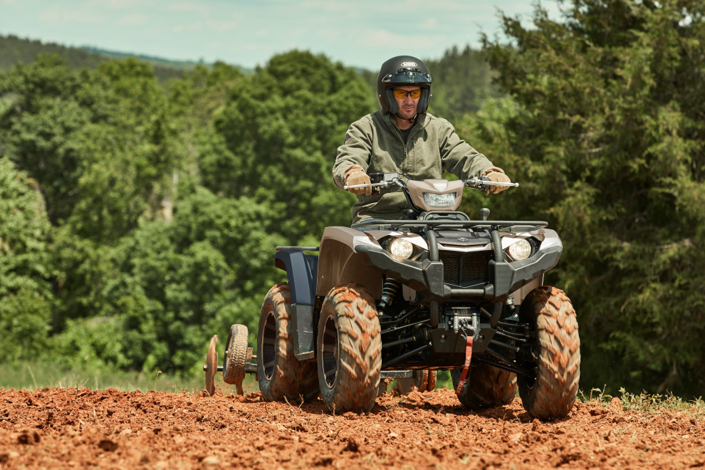 Man op Yamaha ATV op modderig terrein met sleep erachter